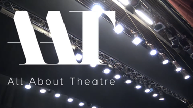Immagine che presenta delle luci da palcoscenico. A sinistra ci sono tre lettere bianche scritte in grande: "AAT", iniziali di "All About Theatre".