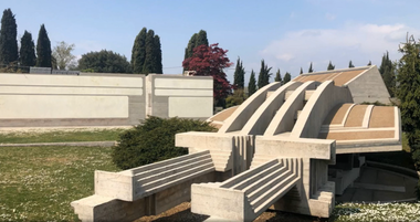 Foto del Memoriale Brion, struttura in cemento caratterizzata da linee nette e volumi geometrici che si erge nel paesaggio circostante. L'immagine mostra la parte centrale del complesso funerario, con la sua forma a conchiglia e le scalinate che conducono alla cappella.