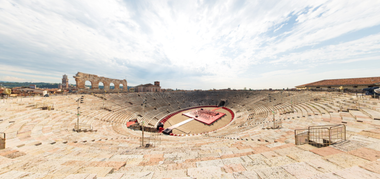 Panoramica dell'Arena di Verona che mostra la sua struttura ellittica, con le gradinate in pietra e il palcoscenico centrale.