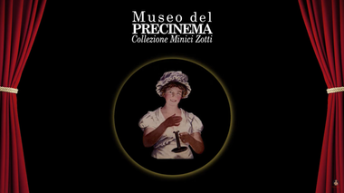 Logo del "Museo del Precinema. Collezione Minici Zotti", su sfondo nero. Al centro è ritratta una donna che tiene in mano un'antica lanterna magica. Un sipario rosso incornicia la scena ai lati.