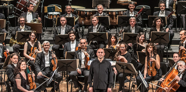 Foto dei musicisti dell'orchestra di Padova e del Veneto: sono tutti seduti, ad eccezione del direttore, e hanno in mano i loro strumenti musicali.
