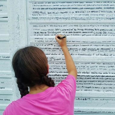 Una bambina scrive una parte de "Le avventure di Pinocchio" su un muro