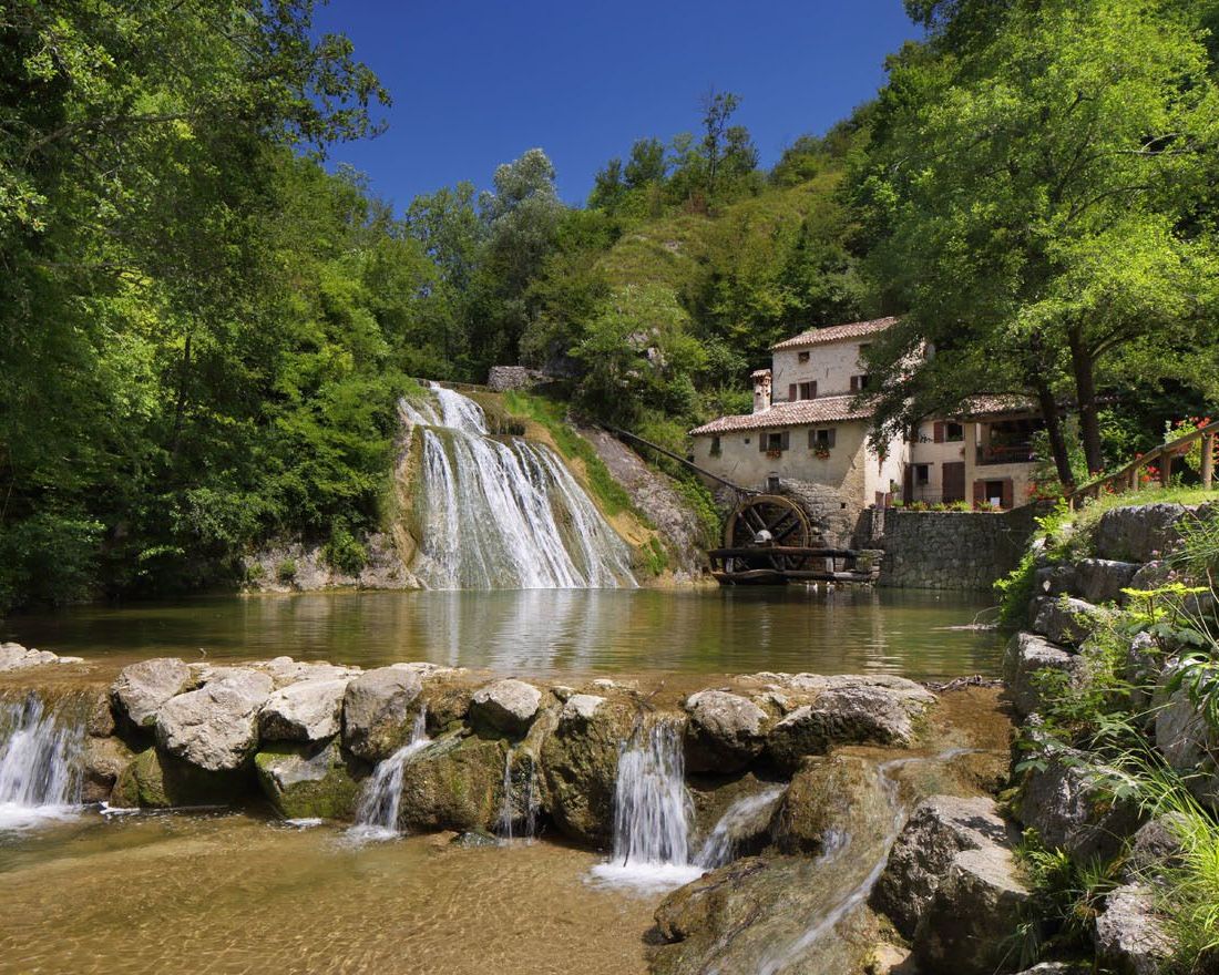 Veduta del mulinetto di Refrontolo immerso nel verde. In primo piano il laghetto creato dalla cascata.
