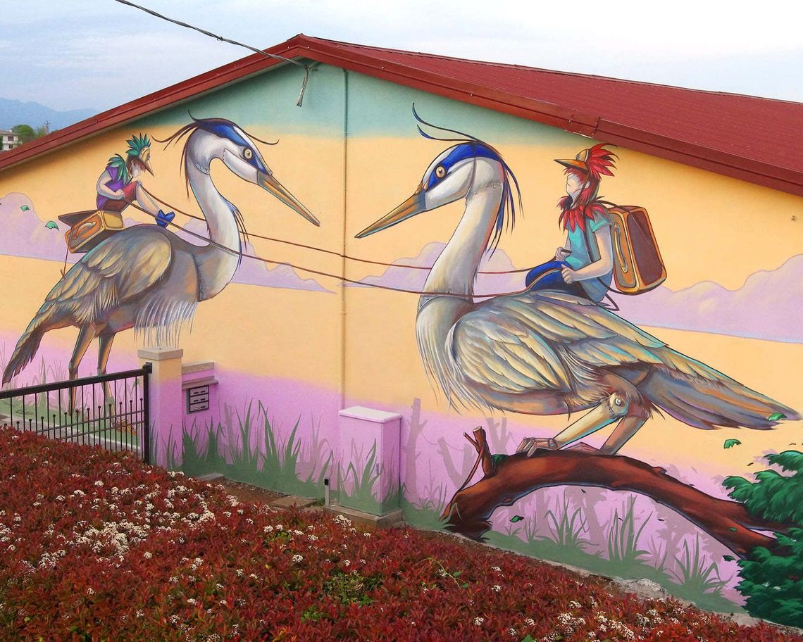 Murale di due giovani che cavalcano due aironi uniti da un filo