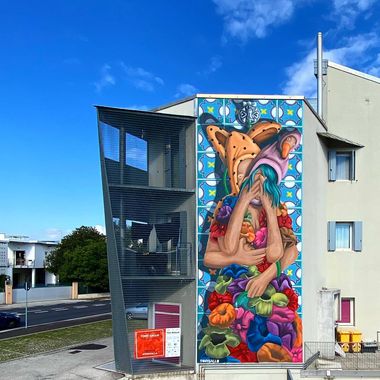 Murale con due figure che si abbracciano mentre con la pompa una annaffia i fiori del vestito dell'altra.