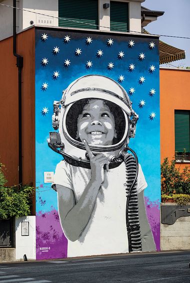 Murale di un bambino che indossa un casco da astronauta e guarda il cielo stellato