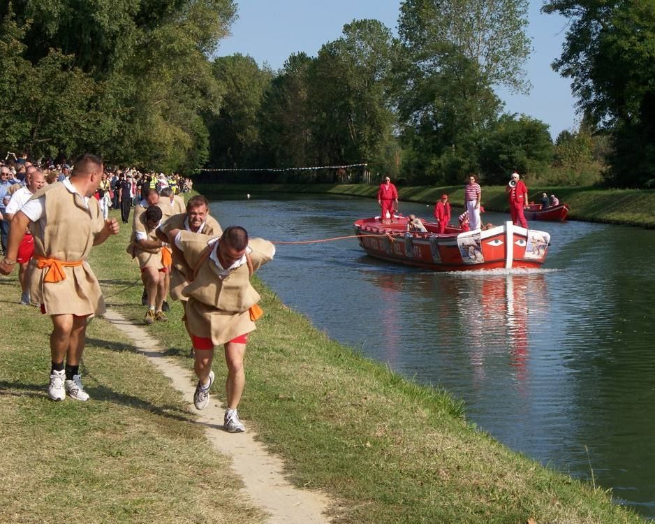 uomini in costume in riva al fiume tirano con la fune un'imbarcazione nel fiume