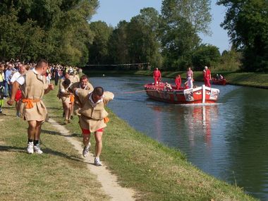 uomini in costume in riva al fiume tirano con la fune un'imbarcazione nel fiume
