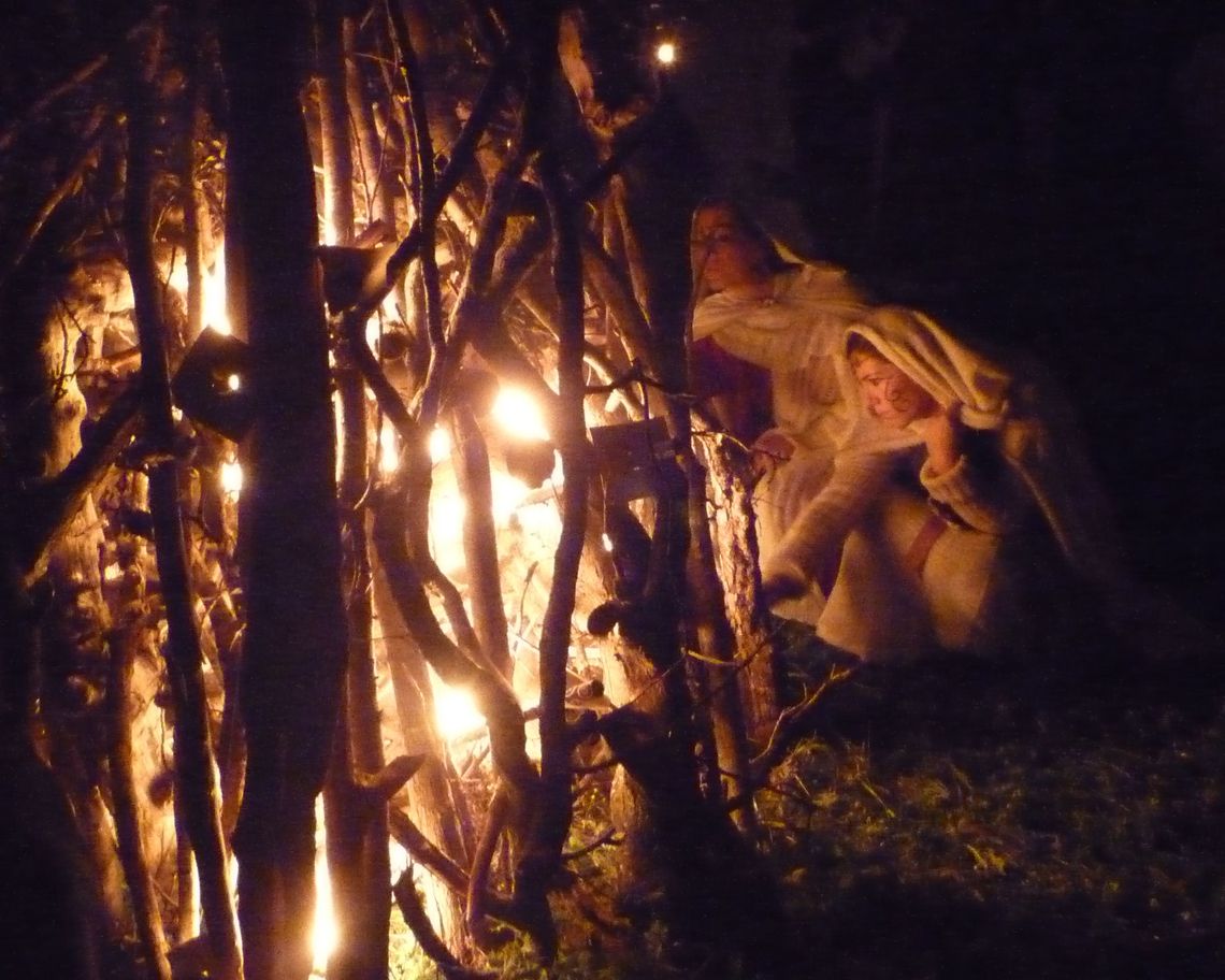 Foto notturna con ragazza inginocchiata con cappuccio che accende il fuoco