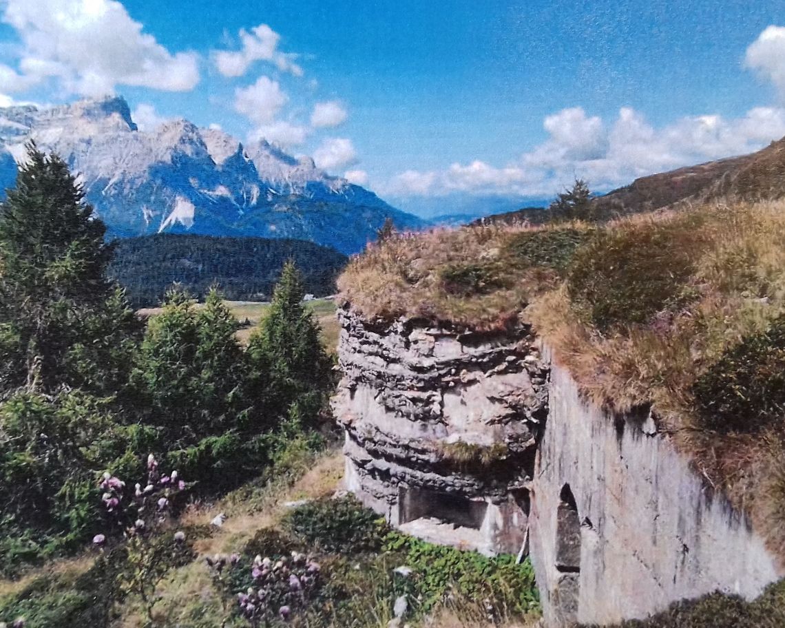 fortificazioni in roccia su prati con montagne sullo sfondo