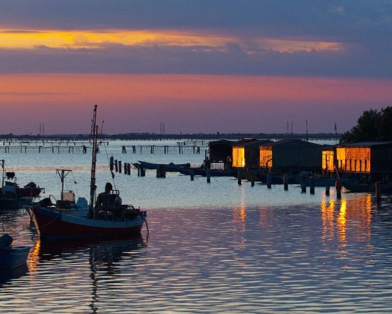 barca con pescatori e casoni al tramonto