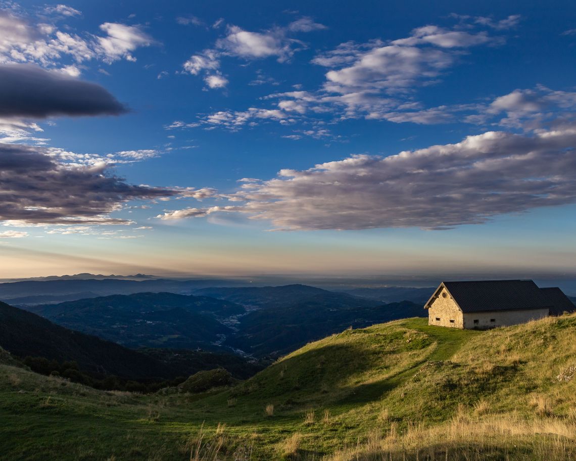 Malga in collina con nuvole sullo sfondo