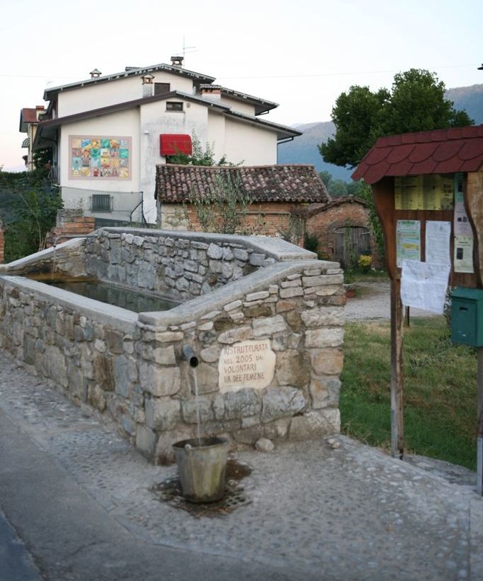 fontana con sullo sfondo una casa con murale colorato sulla parete