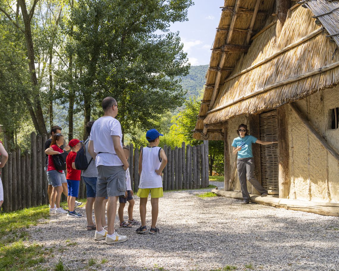 una guida spiega ai visitatori all'ingresso di una palafitta