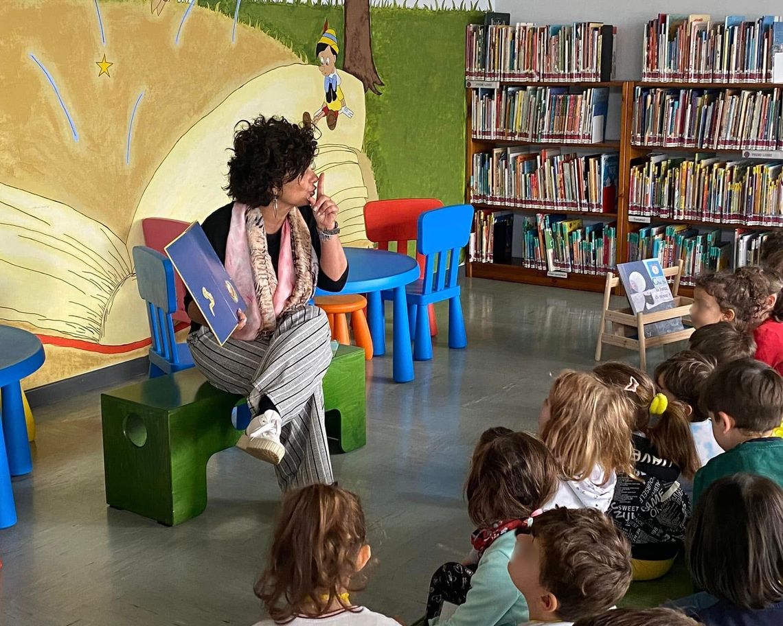 Bambini in cerchio in biblioteca che ascolatno i racconti di una lettrice