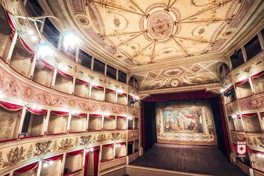 Foto dell'ampia sala dei Teatro de la Sena di Feltre, con stucchi dorati e affreschi. Ha un aspetto regale, il soffitto molto alto e gli spalti strutturati in stile italiano. Molto illuminato.