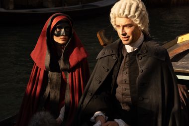 foto di scena che riprende gli attori tecla insolia e michele riondino nei pannni di Cecilia e Antonio Vivaldi. Indossano abiti d'epoca, lei un mantello largo rosso e una maschera nera a coprirne parte del viso, lui porta una parrucca bianca a boccoli tipica del costume maschile del settecento, un mantello nero e abiti semplici ma eleganti. Hanno una luce puntata addosso con alcune ombre proiettate forse da una finestra. Si trovano uno di fianco all'altra e stanno parlando.