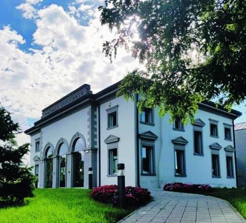 Edificio bianco con trea rchi a vetrata e giardino