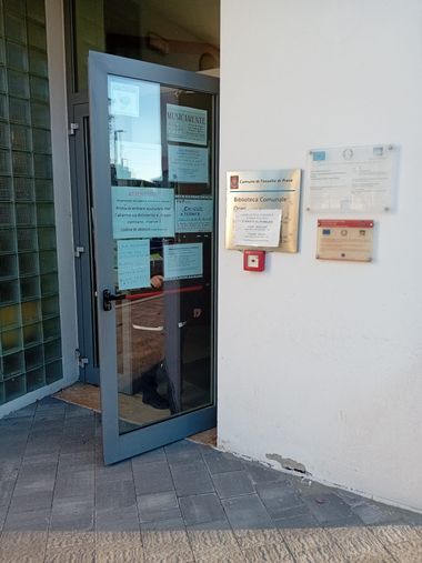 Biblioteca esterno, particolare della porta d'ingresso di vedtro con varie locandine appese