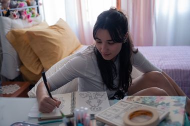 Giulia seduta sulla scrivania colora un album da disegni