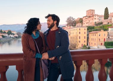 Una donna e un uomo si guardano appaggiati al parapetto sul ponte di bassano
