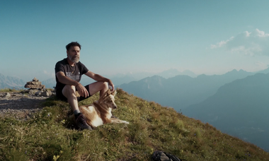 Matteo Righetto seduto su una cima con il cane