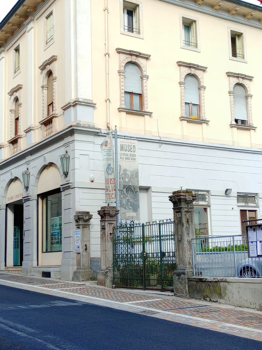 Facciata esterna di un edificio storico a tre piani, ingressi ad arco e cancello in ferro
